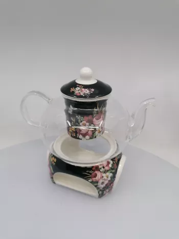 Sklenený čajník a keramický kvetinový ohrievadlom na čiernom podklade